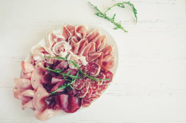 Soğuk et tabağı ile domuz eti, jambon, salam, bresaola ve roka Beyaz ahşap zemin üzerinde füme. Şarap meze küme. İtalyan yemeği. Üstten Görünüm. Kopya alanı.