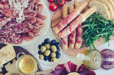 Akdeniz mezeleri, tapas ya da antipasto dolu bir masa. Çeşitli İtalyan yemek takımları. Partide ya da piknikte lezzetli atıştırmalıklar. Et ve peynirli kıyma tahtası. İtalyan usulü ziyafet. Üst görünüm.