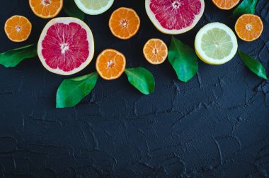 Karışık narenciye arka plan. Metin için yer ile siyah taş tabloda yaprakları ile çeşitli taze meyve. Limon, greyfurt, mandalina. Hasat kavramı. Beslenme, diyet sağlıklı. Üstten Görünüm. Kopya alanı.