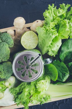 Sağlıklı yeşil smoothie malzemeler bir mason kavanoza Detoks: ıspanak, kereviz, salatalık, marul, zencefil, rezene, kireç ve brokoli siyah arka plan üzerine bir tepsi. Temiz kavramı yeme. Üstten Görünüm.