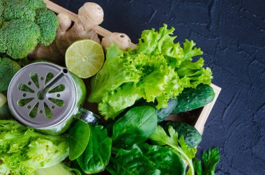 Malzemeler bir mason kavanoza sağlıklı yeşil sebze suyu: ıspanak, kereviz, salatalık, marul, zencefil, rezene, kireç ve brokoli siyah arka plan üzerine bir tepsi. Bahar Detoks kavramı. Üstten Görünüm.