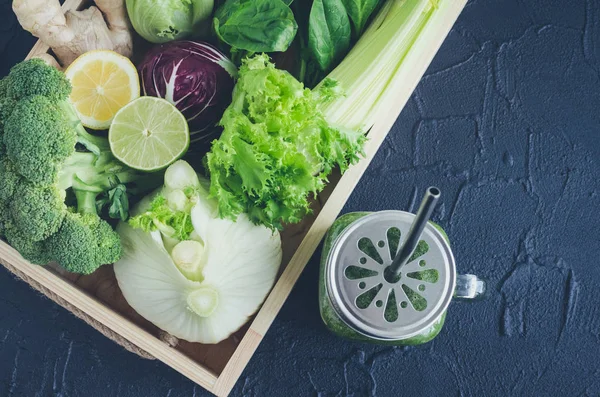 Malzemeler bir mason kavanoza sağlıklı yeşil sebze suyu: ıspanak, kereviz, salatalık, marul, zencefil, rezene, kireç ve brokoli siyah arka plan üzerine bir tepsi. Bahar Detoks kavramı. Üstten Görünüm.