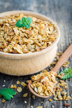 Sağlıklı tahıl aperatifler. Fitness diyet süper yiyecek. Ev yapımı granola. Eski rustik ahşap tahta üzerinde tahta kaşıkla ahşap kase pişmiş gevreği. Nane yaprakları. Vejetaryen vegan beslenme kavramı.