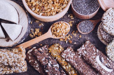 Sağlıklı aperatifler. Diyet yiyecek. Susamlı helva. İnce tabakalar, chia tohum iki kase ve kaşık. Kozinaki, üç enerji bar ve nane. Breadsticks keten ve Ayçiçeği tohumları ile. Eski ahşap tahta. Üstten görünüm.