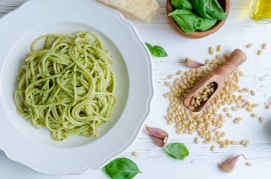 Beyaz ahşap masa üzerinde ev yapımı pesto soslu spagetti. Pesto alla Cenevizli ile makarna. İtalyan mutfağı kavramı. Üstten Görünüm.