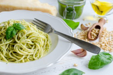 Beyaz ahşap masa üzerinde ev yapımı pesto soslu spagetti. Pesto alla Cenevizli ile makarna. İtalyan mutfağı kavramı.