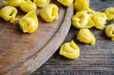 Ev yapımı taze hazırlanmış çiğ et flouring tortellini ahşap vintage kesme tahtası üzerinde pişirmek hazır dolu. Geleneksel İtalyan mutfağı kavramı. Seçici odak.