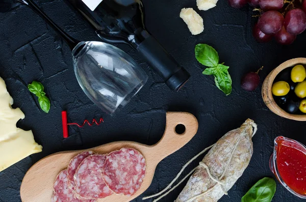 Bottle of wine, corkscrew and antipasti. Table full of mediterranean appetizers or antipasto. Assorted Italian style banquet party food set. Tradition wine tasting concept. Top view.