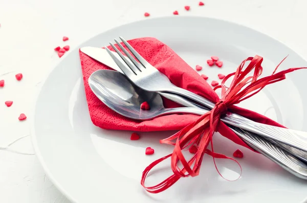 Close up view of restaurant table with romantic place setting with plates, cutlery on white background. Valentine\'s Day or romantic dinner concept. Valentine day or proposal background.