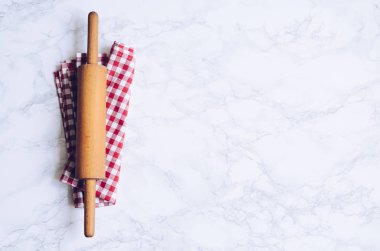 Metin için yer mermer zemin üzerine kırmızı kareli peçete üzerinde ahşap oklava. Ders poster - düzen serbest metin alanı ile yemek. Fırın kavramı arka plan. Üstten görünüm. Kopya alanı.