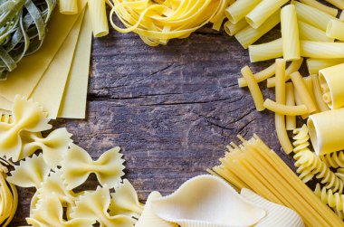 Çerçeve türü ve İtalyan makarna yukarıdan eski ahşap arka plan üzerine şekiller. İtalyan mutfağı gıda kavramı ve menü tasarımı. Kuru makarna arka plan. Üstten görünüm. Düz yatıyordu. Kopya alanı.