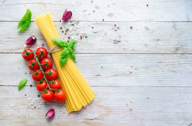 İtalyan pasta - yemek pişirmek için malzemeler spagetti, domates, fesleğen ve sarımsak metniniz için yer ile eski rustik ahşap masa üzerinde ahşap tahta üzerinde. İtalyan mutfağı kavramı. Uzay kopyalayın. Üstten görünüm.