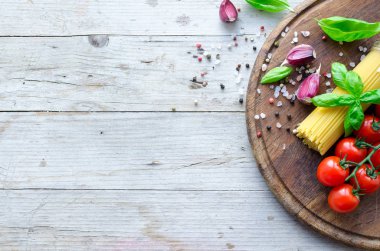 İtalyan pasta - yemek pişirmek için malzemeler spagetti, domates, fesleğen ve sarımsak metniniz için yer ile eski rustik ahşap masa üzerinde ahşap tahta üzerinde. İtalyan mutfağı kavramı. Uzay kopyalayın. Üstten görünüm.