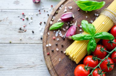 İtalyan pasta - yemek pişirmek için malzemeler spagetti, domates, fesleğen ve sarımsak metniniz için yer ile eski rustik ahşap masa üzerinde ahşap tahta üzerinde. İtalyan mutfağı kavramı. Uzay kopyalayın. Üstten görünüm.