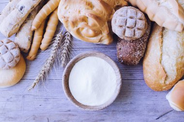 Geleneksel İtalyan farklı türde fırından yeni çıkmış ekmek ve un ahşap masa arka plan üzerinde kase ile buns. Rustik vintage tarzı. Üstten görünüm.