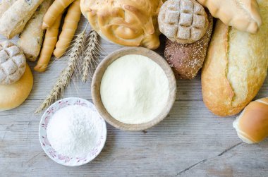 Geleneksel İtalyan farklı türde fırından yeni çıkmış ekmek ve un ahşap masa arka plan üzerinde kase ile buns. Rustik vintage tarzı. Üstten görünüm.