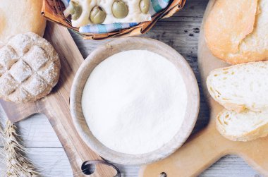 Geleneksel İtalyan farklı türde fırından yeni çıkmış ekmek ve un ahşap masa arka plan üzerinde kase ile buns. Rustik vintage tarzı. Üstten görünüm.