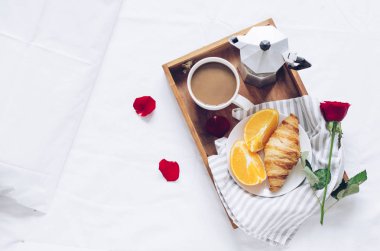Romantik Sevgililer günü yatak, taze kruvasan ile tepsi, fincan kahve espresso süt, taze portakal ve kırmızı gül ile odaya. Günaydın kavramı. Yavaş hayattan zevk. Üstten görünüm. Kopya alanı.