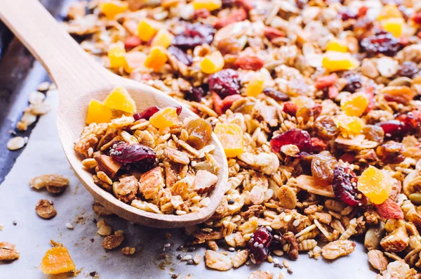 Homemade roasted granola on baking sheet with sesame, pumpkin, sunflower and chia seeds, goji berries, dates and raisins, cranberries, dried apricots, nuts and almonds. Superfood.