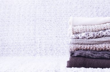 Yünlü yün kazak yığını. Monokrom eğimli gölgeler gri beyaz siyah renkler farklı örgü desenleri yığılmış giysiler. Sıcak kış kış sonbahar örgü konsepti. Boşluğu kopyala.