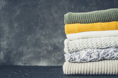 Sonbahar renkleri örülmüş yün kazak yığını. Farklı örgü desenleri olan giysiler yığınla. Sıcacık kış sonbahar örgü konsepti. Boşluğu kopyala.