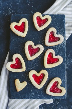 Kalp siyah arka plan üzerinde Sevgililer Günü için reçel ile Linzer çerezleri şeklinde. Lezzetli ev yapımı pasta. Aşk konsepti ile pişirme. Üstte görüntü.