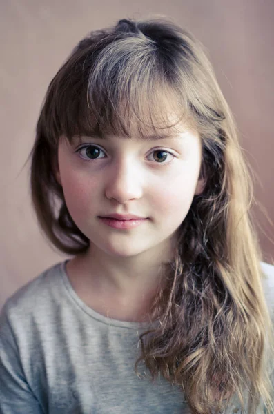 Sevimli gülümseme ile küçük güzel kız portresi. Uzun koyu sarı saçları ve harika ilgilenmek kahverengi gözlü güzel kızla. Küçük hanım kız öğrenci 8 yaşında. Yakın çekim. Rüya gibi iyimser görünümü.