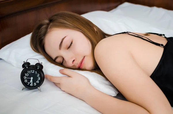 Young woman sleep with alarm clock on the bed in the morning. Sleeping girl and alarmclock in bedroom at home. Student or schoolgirl afraid to wake up late. Alarm clock anxiety. Oversleep concept.