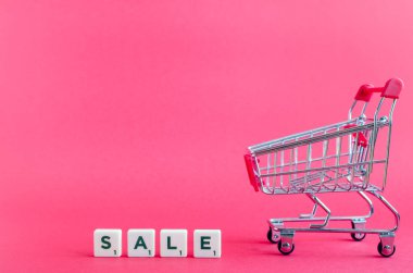 Boş bakkal arabası ve kelime Satış pembe arka plan üzerinde. Süpermarketten tramvay. Online alışveriş konsepti Black Friday ve Ciber Pazartesi. Kopyalama alanı.