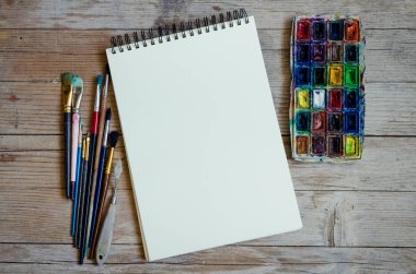 Yaratıcı sanatçı çalışma alanı düz yatıyordu, mockup. Üstten görünüm tablo boş sketchbook, boya fırçaları ve boya paletleri ile. Sanat Atölyesi, resim, çizim, el sanatları, yaratıcılık kavramı. Kopya alanı.