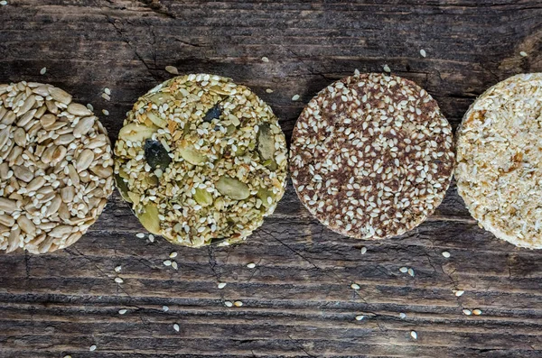 Dessert cereal snacks. Fitness dietary food. Kozinaki with sesame, peanuts, sunflower and pumpkin seeds, dates on old rustic wooden board. Vegan healthy nutrition concept. Top view. Copy space.