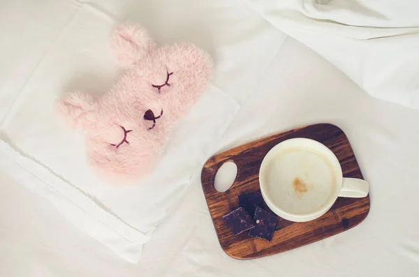 Чашка кофе в розовой маске для сна — стоковое фото