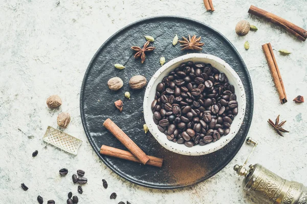 Coffee beans with spices over black plate