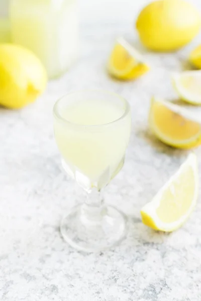 Traditional homemade lemon liqueur limoncello and fresh citrus on the table. Italian traditional liqueur limoncello with lemon. Italian alcoholic beverage.