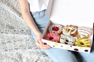 Lezzetli çöreklerle dolu bir kutu tutan kadın. Parti konsepti. Diyet yok. Çikolata. Düzgün beslenme ya da tatlı, tatlı fast food, diyet sabah konsepti.