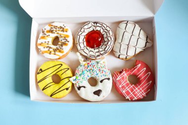 Donut kutusu koyu arka planda. Beyaz jöleli, modaya uygun tek boynuzlu at. Üst görünüm veya düz uzanma.