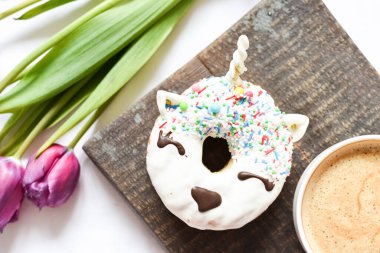 Mor laleli tek boynuzlu at çöreği ve kahve. Beyaz jöleli, modaya uygun tek boynuzlu at. Sevdiklerine romantik sevgililer günü kahvaltısı. Anneler Günü konsepti. Annemin hediyesi. Üst görünüm.