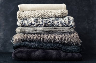 Yünlü yün kazak yığını. Monokrom eğimli gölgeler gri beyaz siyah renkler farklı örgü desenleri yığılmış giysiler. Sıcak kış kış sonbahar örgü konsepti. Boşluğu kopyala.