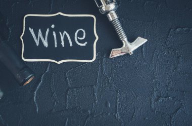 Siyah taş arka planda tirbuşonlu bir şişe şarap. Geleneksel şarap yapımı ve şarap tatma konsepti. Üst Manzara. Boşluğu kopyala.