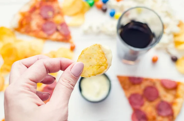 Fast food and unhealthy eating concept. Close up of fastfood snacks: pizza, popcorn, potato chips and candies. Assortment of carbohydrates products bad for figure, skin, heart and teeth. Top view.