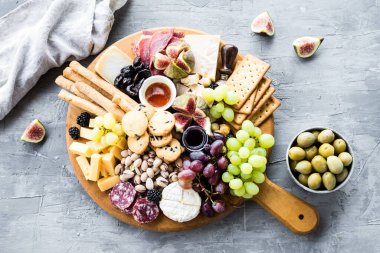 Şarküteri tahtası. Peynir tabağı: parmesan, maasdam, camembert, cheddar, gouda prosciutto, salam, meyve ve fındıklı. Lezzetli aperatifler ya da antipastalar. Üst Manzara. Boşluğu kopyala.