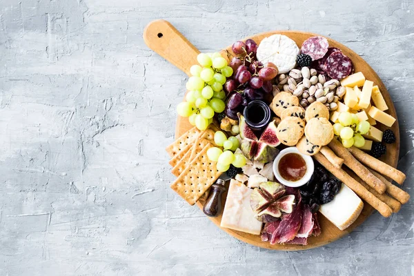 Şarküteri tahtası. Peynir tabağı: parmesan, maasdam, camembert, cheddar, gouda prosciutto, salam, meyve ve fındıklı. Lezzetli aperatifler ya da antipastalar. Üst Manzara. Boşluğu kopyala.