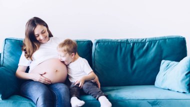 Küçük kardeşim. Evdeki kanepede oturan hamile annesiyle konuşan tatlı bir çocuk. Meraklı çocuk hamile annenin karnını dinliyor. Hamilelik, aile, ebeveynlik ve beklenti kavramları.