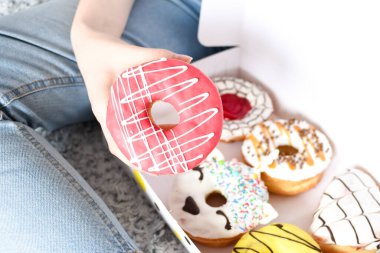 Lezzetli çöreklerle dolu bir kutu tutan genç kadın. Parti konsepti. Diyet yok. Çikolata. Düzgün beslenme ya da tatlı, tatlı fast food. Sağlıksız yaşam tarzı kavramı. Yemek dağıtımından çörekler..