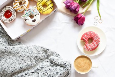 Mor laleli ve kahveli düz çörek kutusu. Romantik Sevgililer Günü kahvaltısı yatakta. Anneler Günü konsepti. Üst Manzara. Boşluğu kopyala.