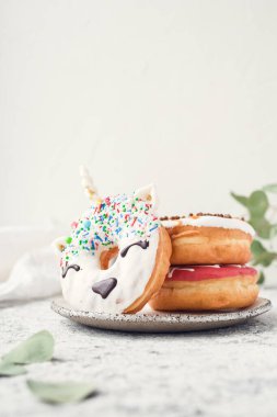 Tek boynuzlu at donutu arka planda. Beyaz jöleli, modaya uygun tek boynuzlu at. Çörek yığını. Boşluğu kopyala.