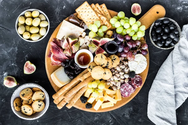 Şarküteri tahtası. Peynir tabağı: parmesan, maasdam, camembert, cheddar, gouda prosciutto, salam, meyve ve fındıklı. Lezzetli aperatifler ya da antipastalar. Üst Manzara. Boşluğu kopyala.