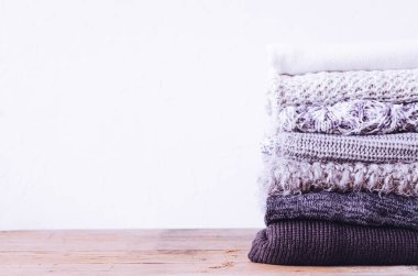 Yünlü yün kazak yığını. Monokrom eğimli gölgeler gri beyaz siyah renkler farklı örgü desenleri yığılmış giysiler. Sıcak kış kış sonbahar örgü konsepti. Boşluğu kopyala.
