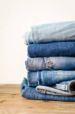 Tahta bir masaya istiflenmiş kot pantolonlar. Denim Tekstil giyim arka plan yığını konsepti. Boşluğu kopyala.