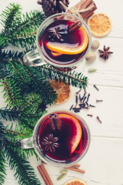 Sıcak kırmızı şarapla portakal, tarçın çubukları ve beyaz ahşap kaplama malzemeli yıldız anason. İki baharatlı sıcak içecek. Mevsimlik Noel içkisi. Uzayı kopyala Üst görünüm.